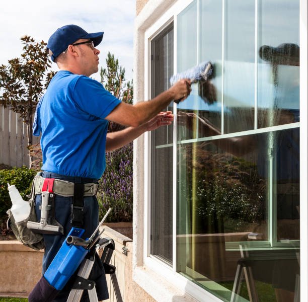 Man cleaning window of a home.