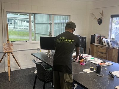 Person organizing a cluttered office space. Office cleaning Auckland North Shore