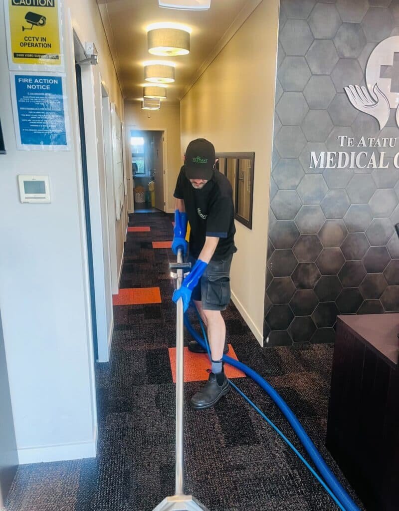 Person cleaning carpet in hallway.